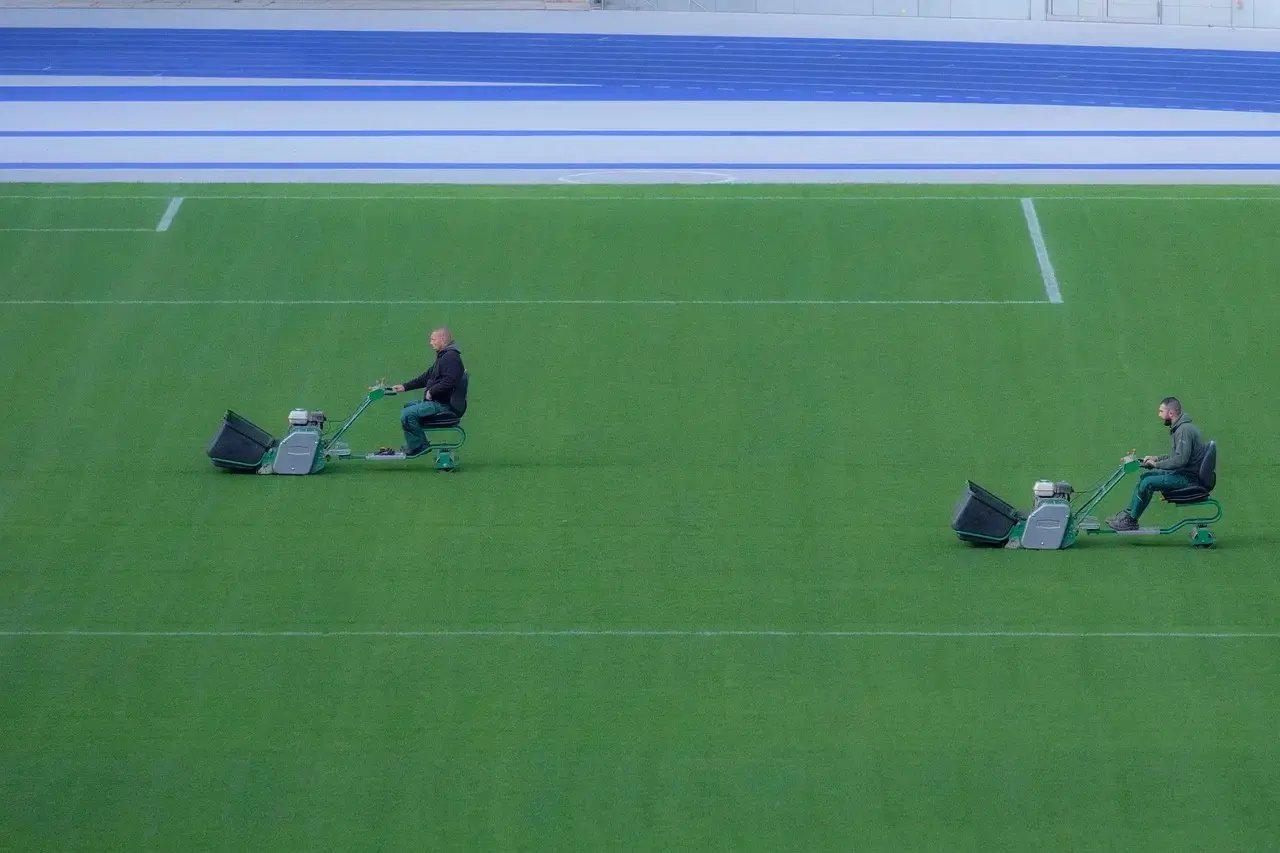 Lawn care crews mowing large field efficiently using a lawn care mobile app for job coordinati