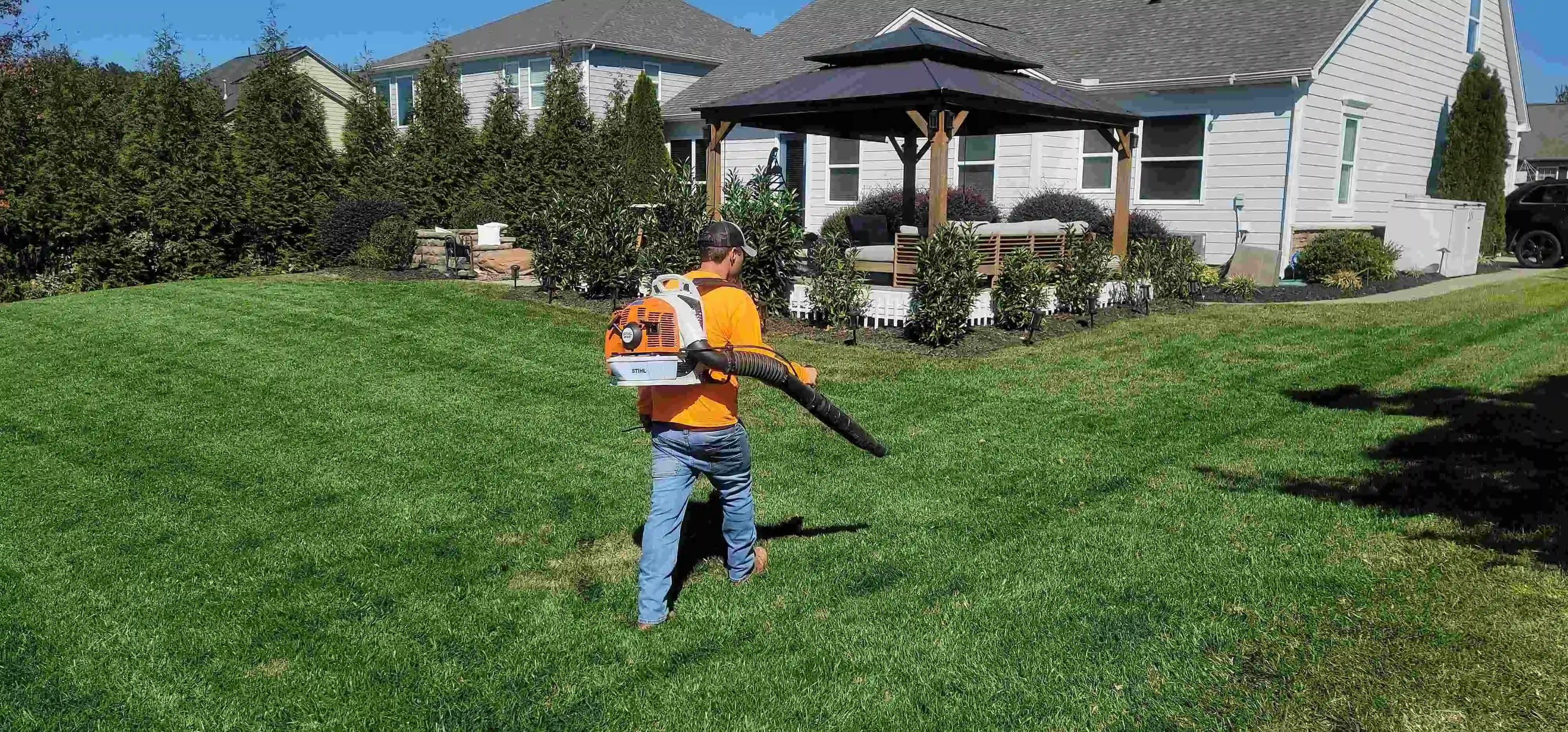 Lawn care professional managing yard maintenance job at a residential property